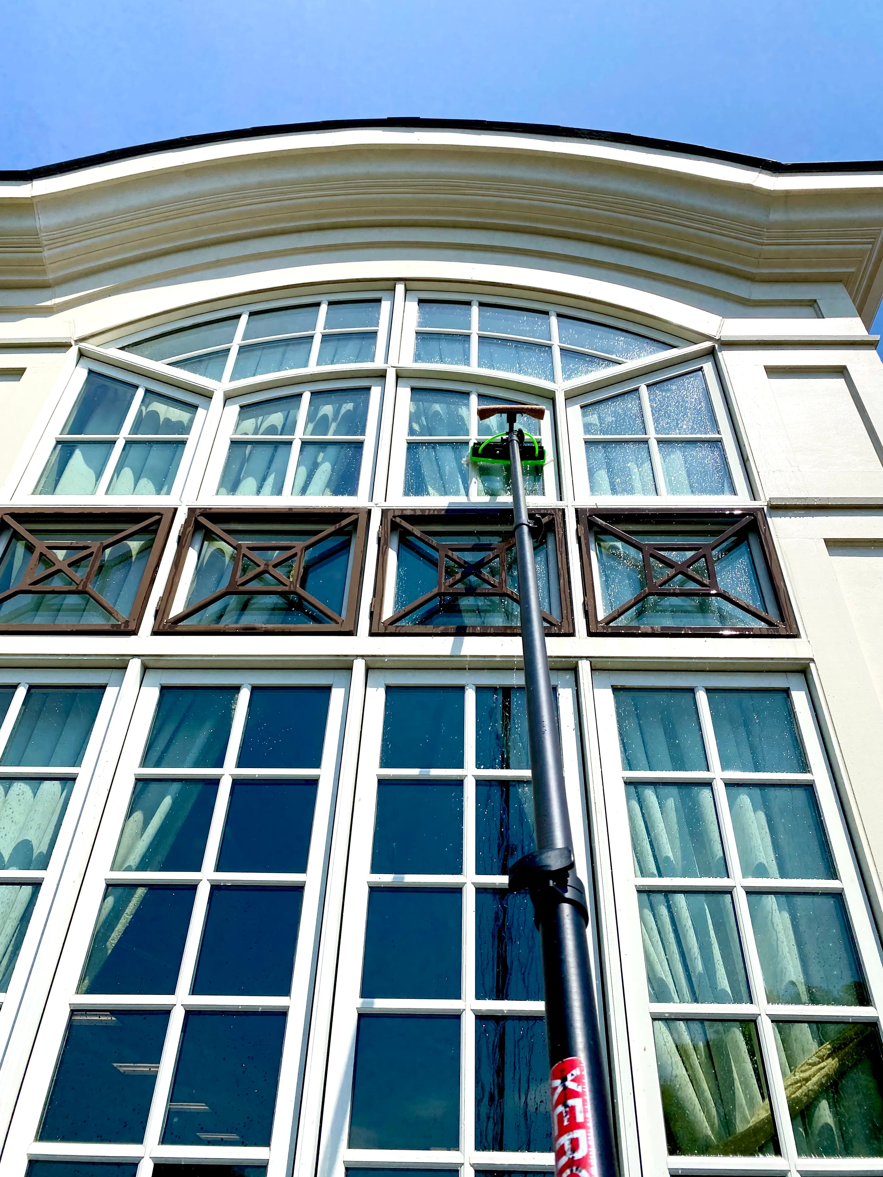 Extension-pole window cleaning on a second-story arched window