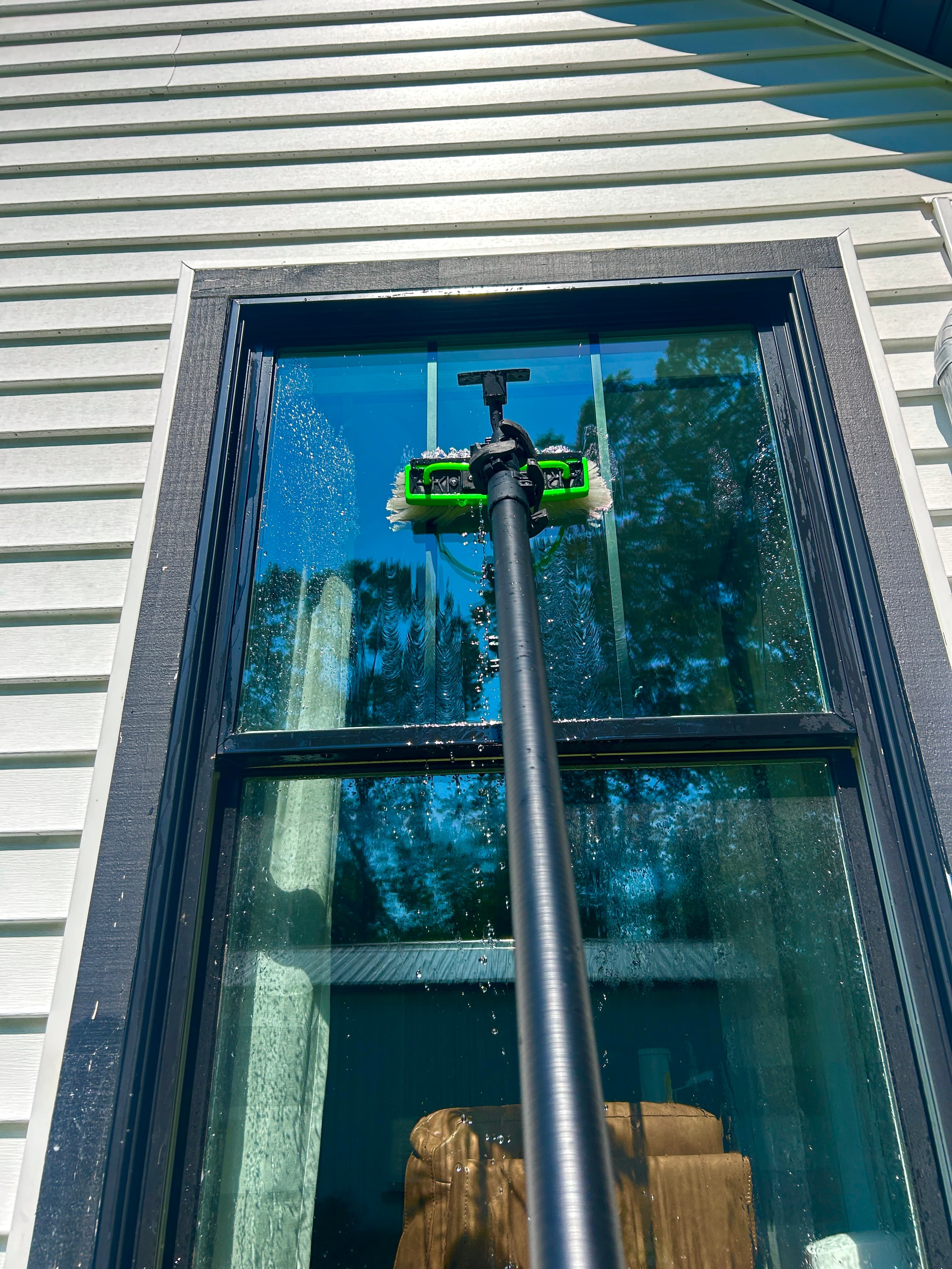 Water-fed pole brush actively cleaning a second-story window